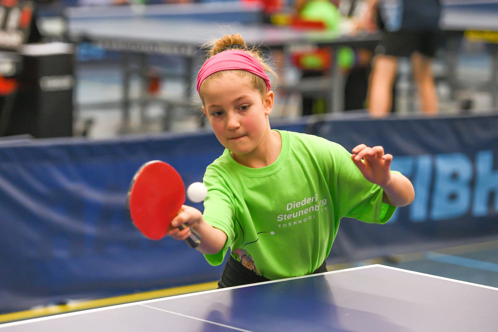 Een jong meisje speelt een wedstrijd tafeltennis tijdens een toernooi